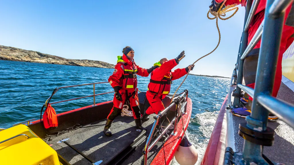 Frivillig sjöräddare står på en enhet och kastar en tross mot en annan