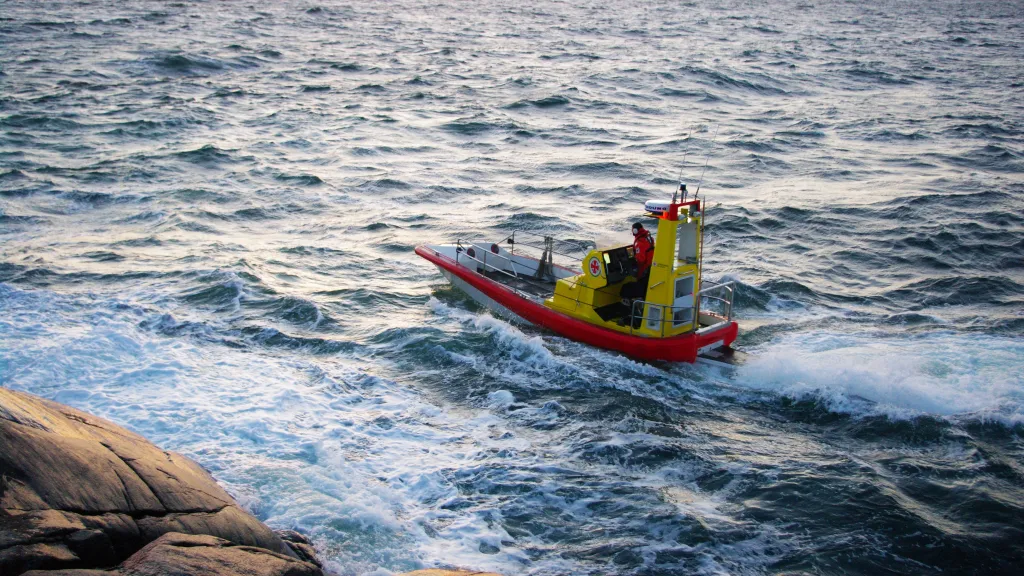 Båt i Gunnel Larsson-klassen kör vid en klippa i solnedgången