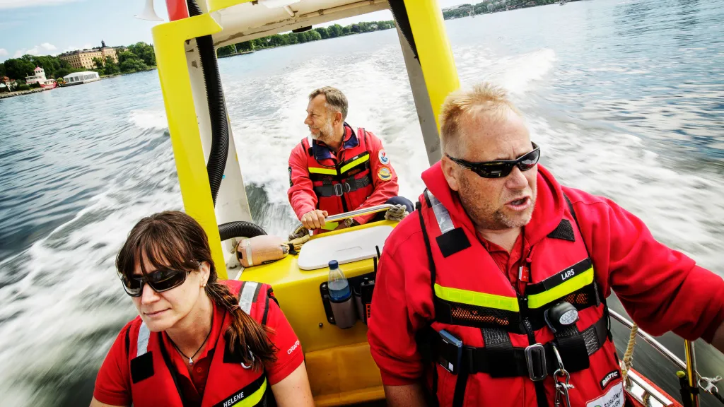 Tre frivilliga sjöräddare tar sig fram på sjön i en öppen båt