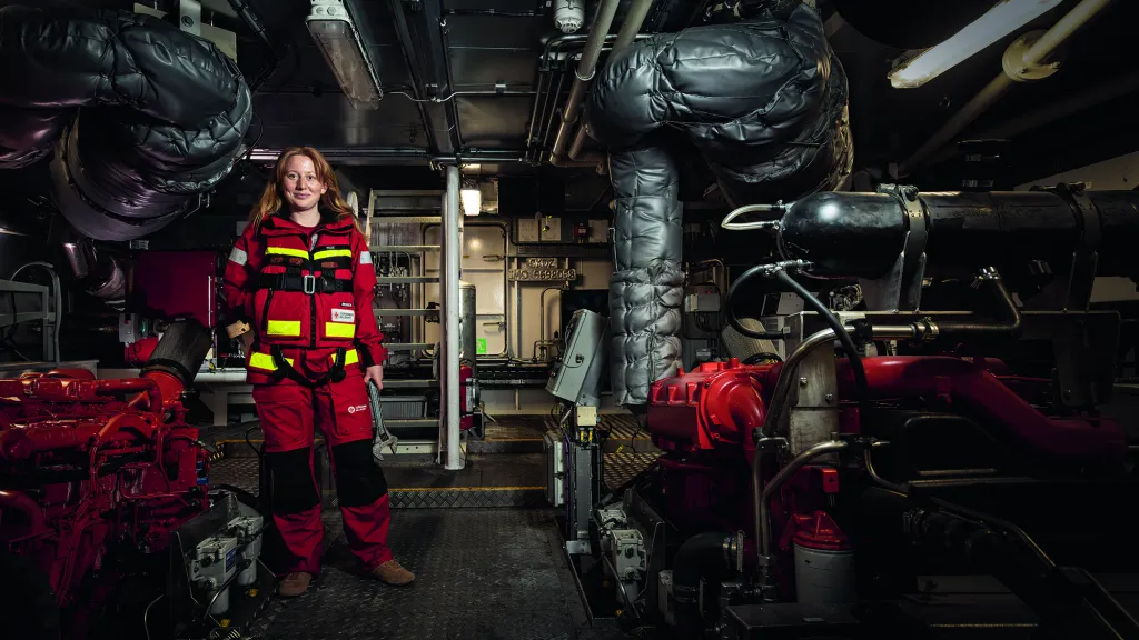 Vilde Vedholm, frivillig på RS Käringön, står nere i ett maskinrum hållandes i en skiftnyckel.