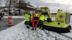 Frivilliga sjöräddare står tillsammans med ambulanspersonal bredvid en svävare
