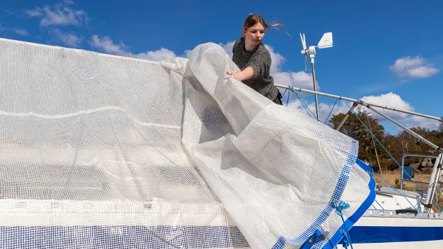 Presenningen tas bort från en segelbåt innan vårrustningen drar igång. 