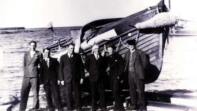 Tidiga sjöräddare står uppradade framför en räddningsbåt