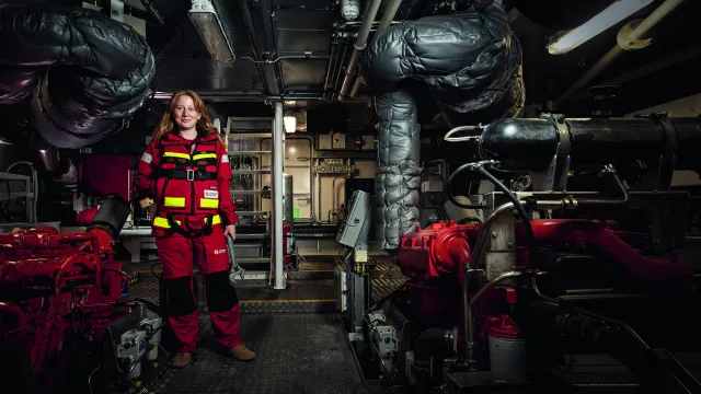 Vilde Vedholm, frivillig på RS Käringön, står nere i ett maskinrum hållandes i en skiftnyckel.