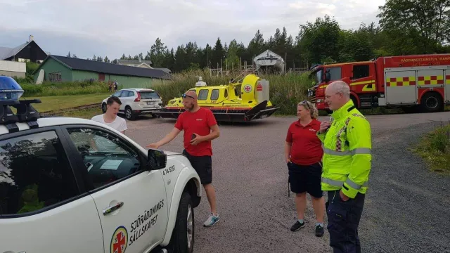 Frivilliga sjöräddare står framför en av Sjöräddingssällskapets bilar.