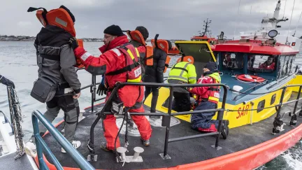 Sjöräddare hjälper nödställda till räddningsbåt