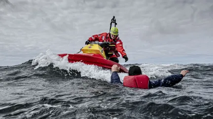 sjöräddare på rescuerunner sträcker ut en hand mot en person i vattnet